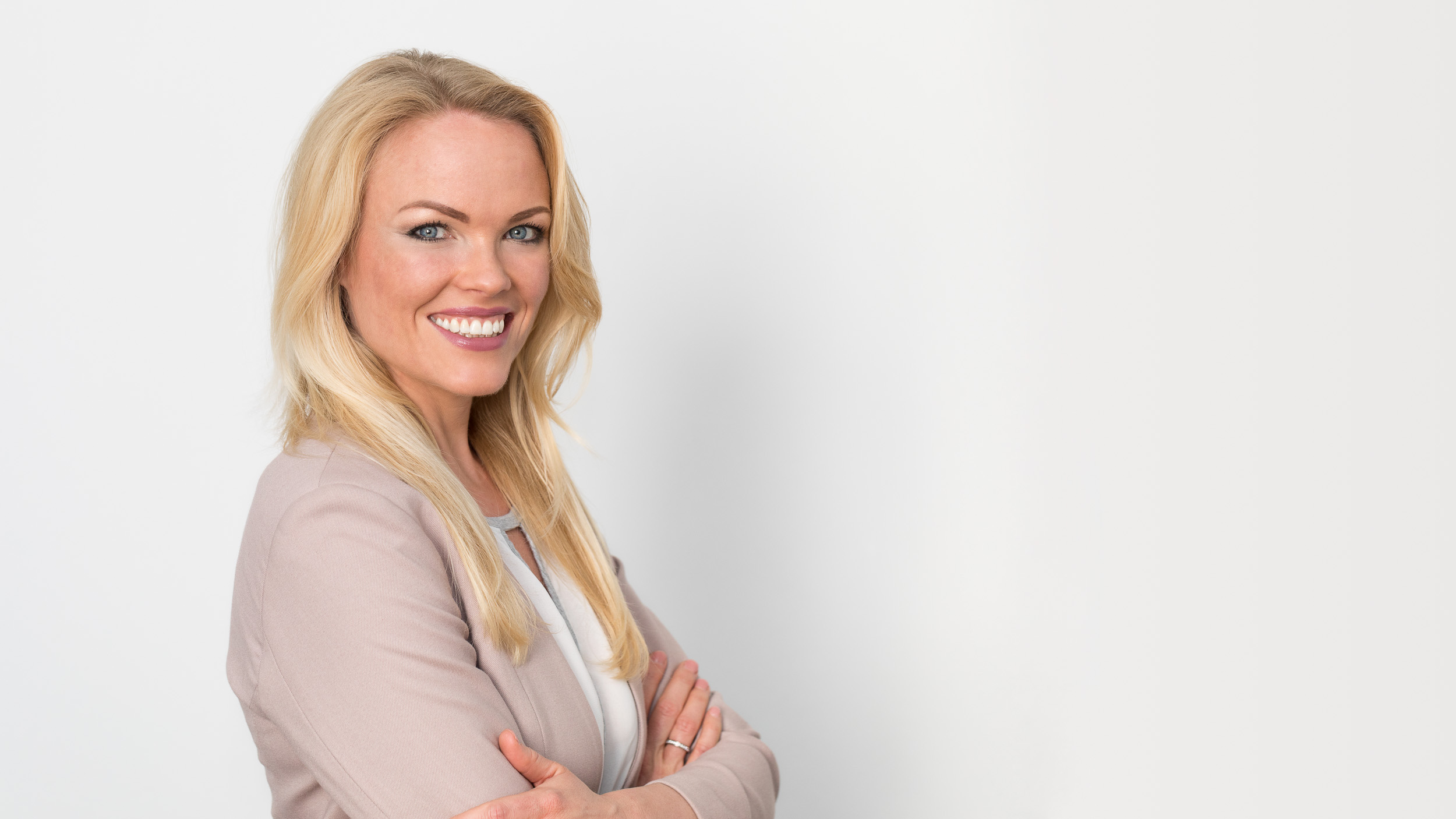 photo-genic: Portraitfotografie – Businessfotografie photo-genic Business Portrait: Lächelnde Geschäftsfrau stehend vor weißer Wand