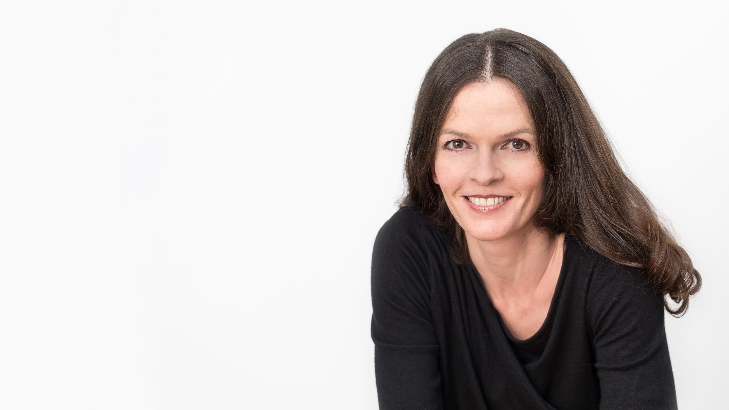 photo-genic: Portraitfotografie – Businessfotografie photo-genic Portraitfotografie: Frau, schwarz gekleidet vor weißer Wand
