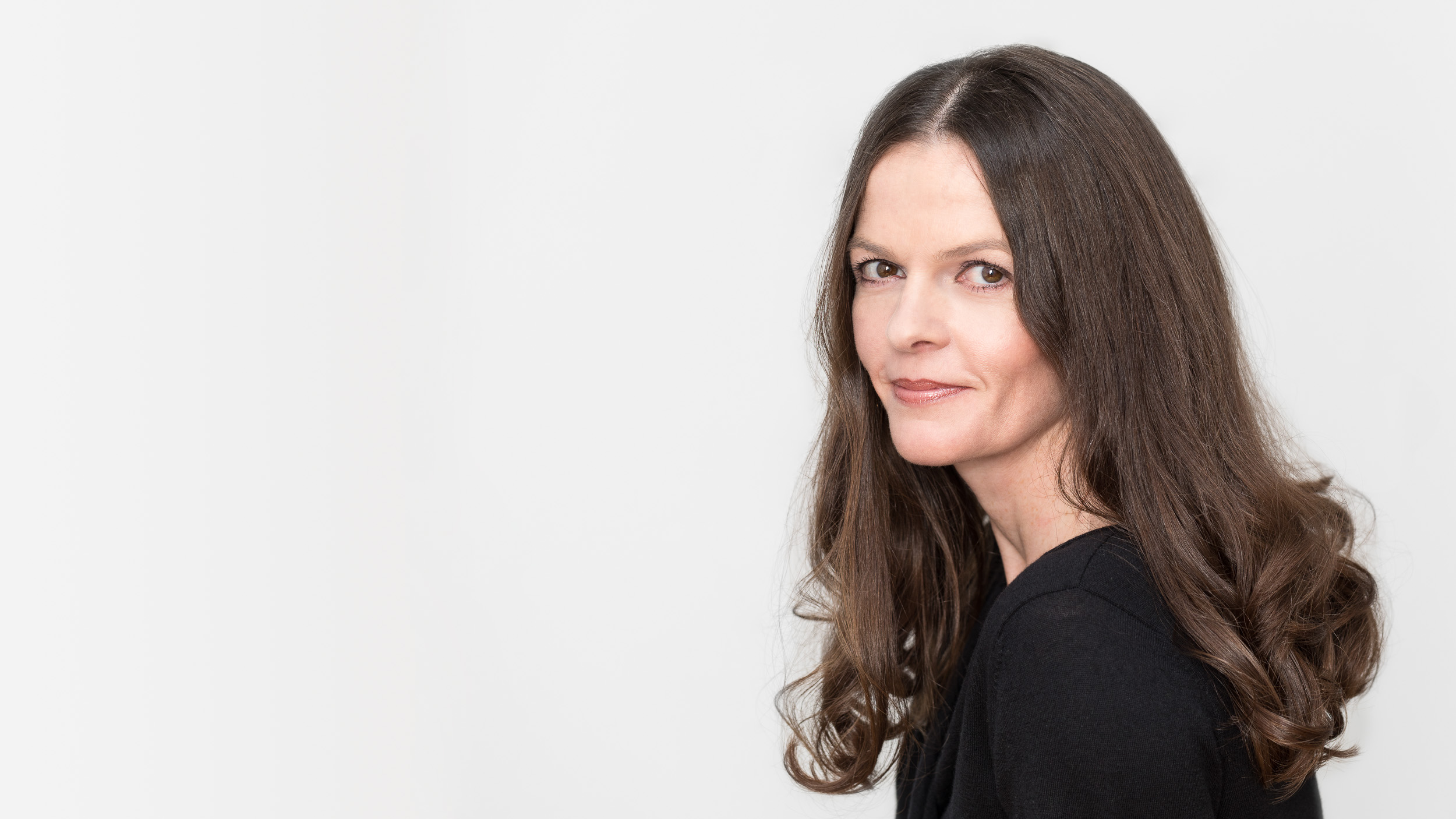 photo-genic: Portraitfotografie – Businessfotografie photo-genic Portraitfotografie: Frau, schwarz gekleidet vor weißer Wand