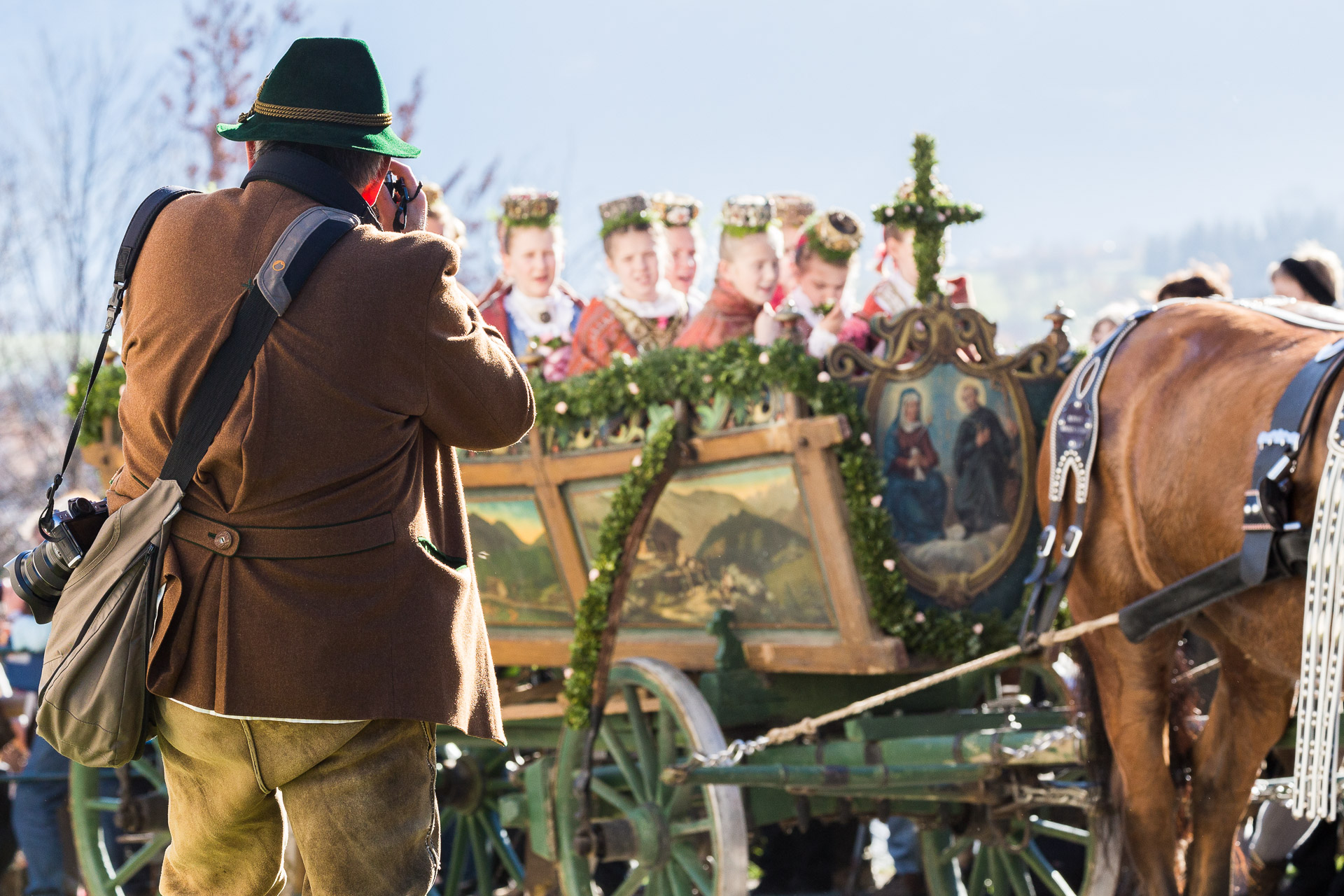 Mann in Tracht fotografiert vorbeifahrenden Kastenwagen mit Mädchen in Tracht. Reportagefotografie - Fotoreportage von photo-genic.