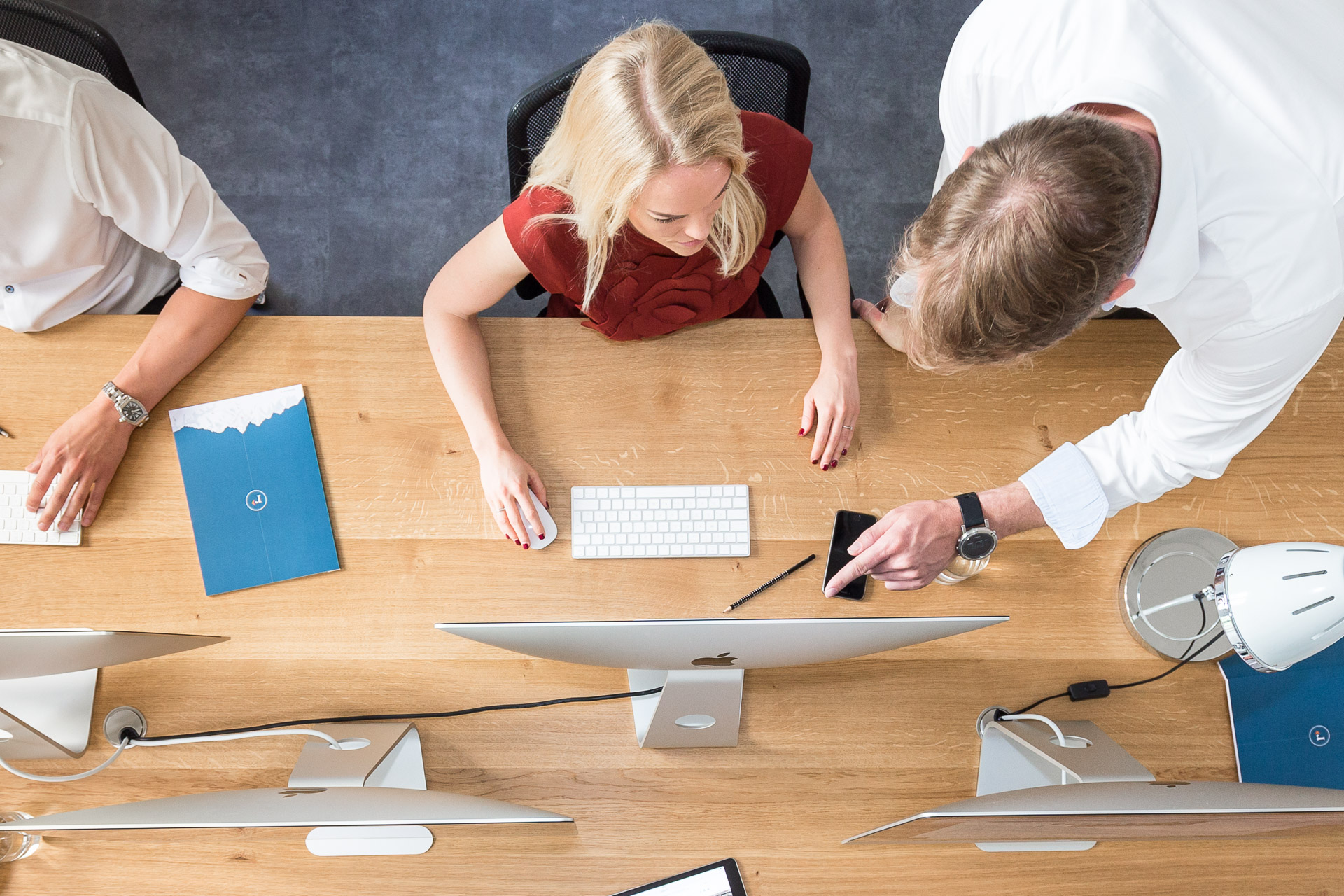 Businessfotografie: Kollege spricht mit Mitarbeiterin und deutet auf deren Bildschirm