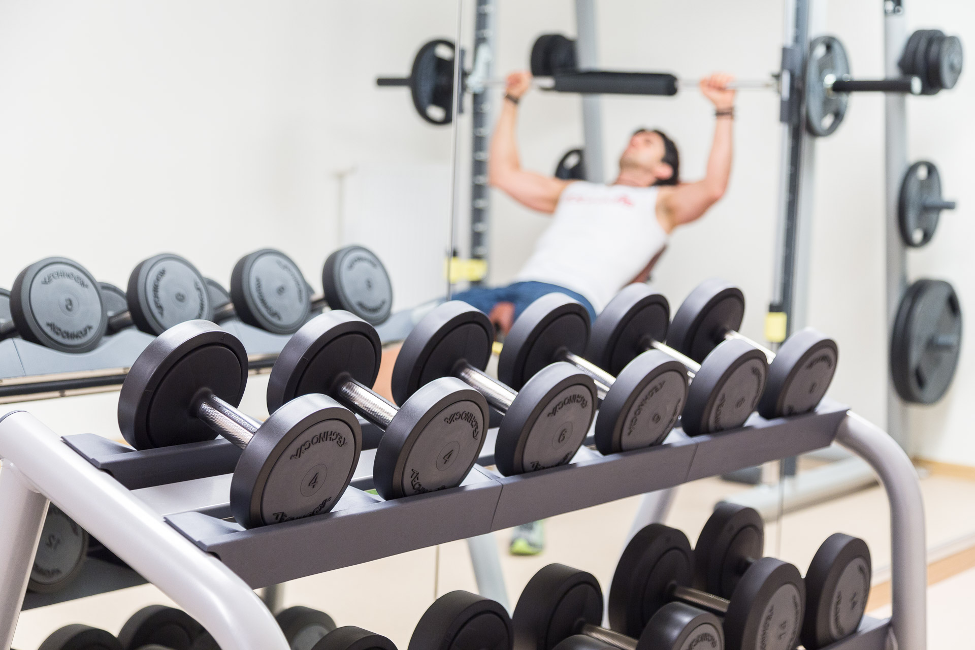 Fitnessraum mit Handeln, Mann trainiert Bankdrücken
