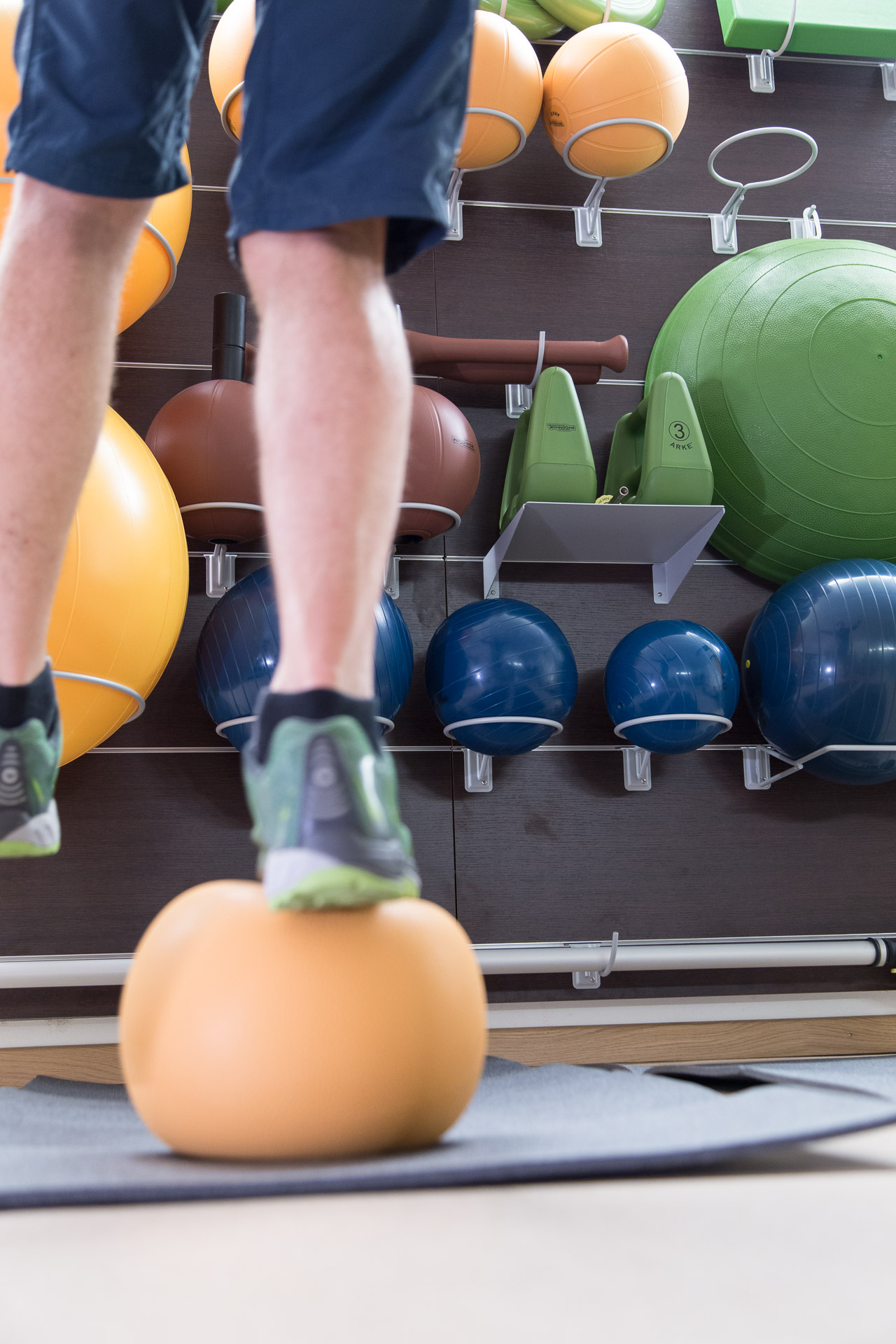 Mann balanciert auf einem Ball im Fitnessraum