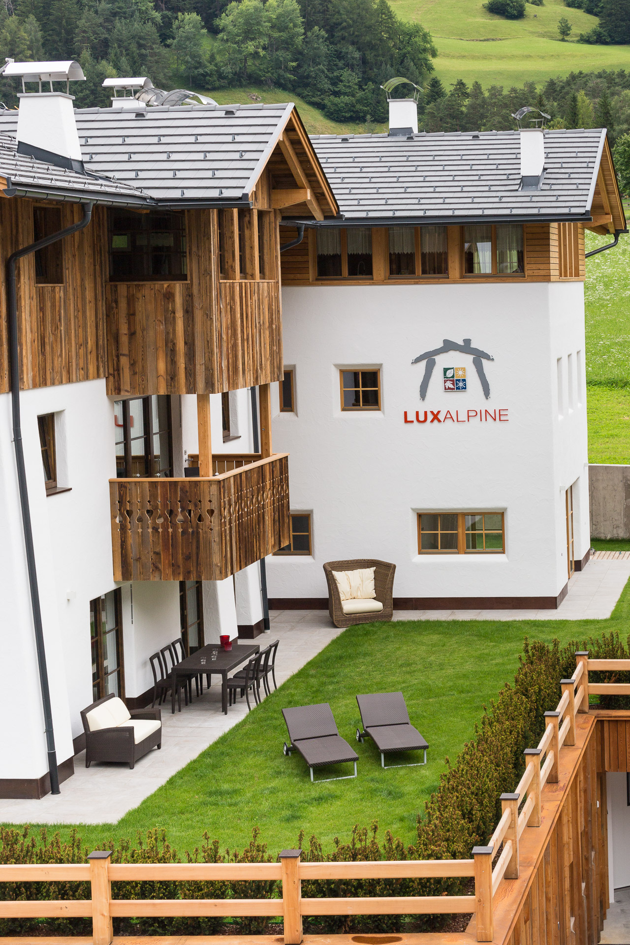 Hotelfotografie: Außenansicht des Ferienhauses mit Blick in den Garten mit Liegen und Sitzkörbe