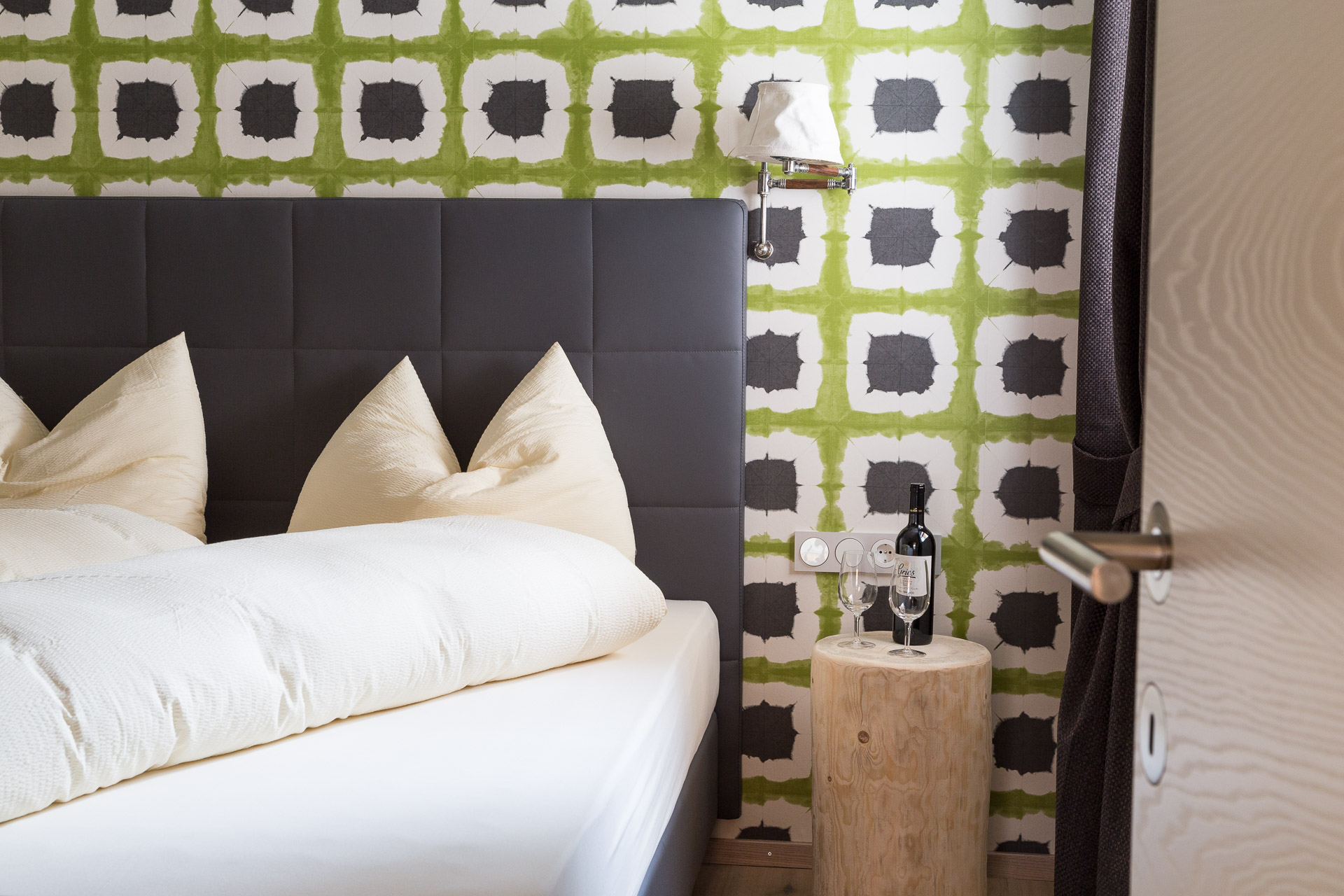 Schlafzimmer mit Doppelbett und Mustertapete an der Rückwand