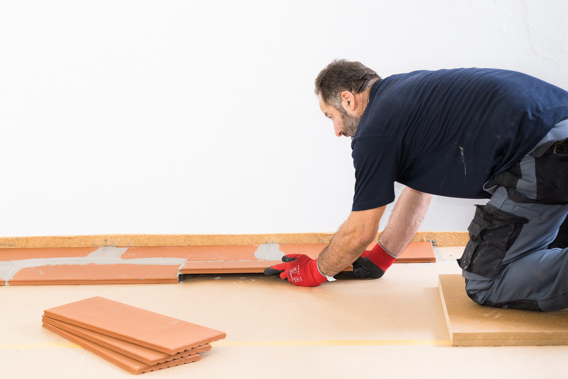 Handwerker verlegt Estrichfziegel auf den Boden. Industriefotografie - Baubranche von photo-genic.